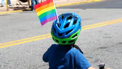 Jeune enfant &agrave; bicyclette portant un casque avec le drapeau arc-en-ciel
