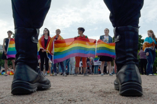 militaire en bottes face &agrave; des manifestants avec banni&egrave;re LGBT