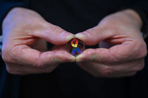 Mains tenant un médaillon VIH aux couleurs de l'arc-en-ciel